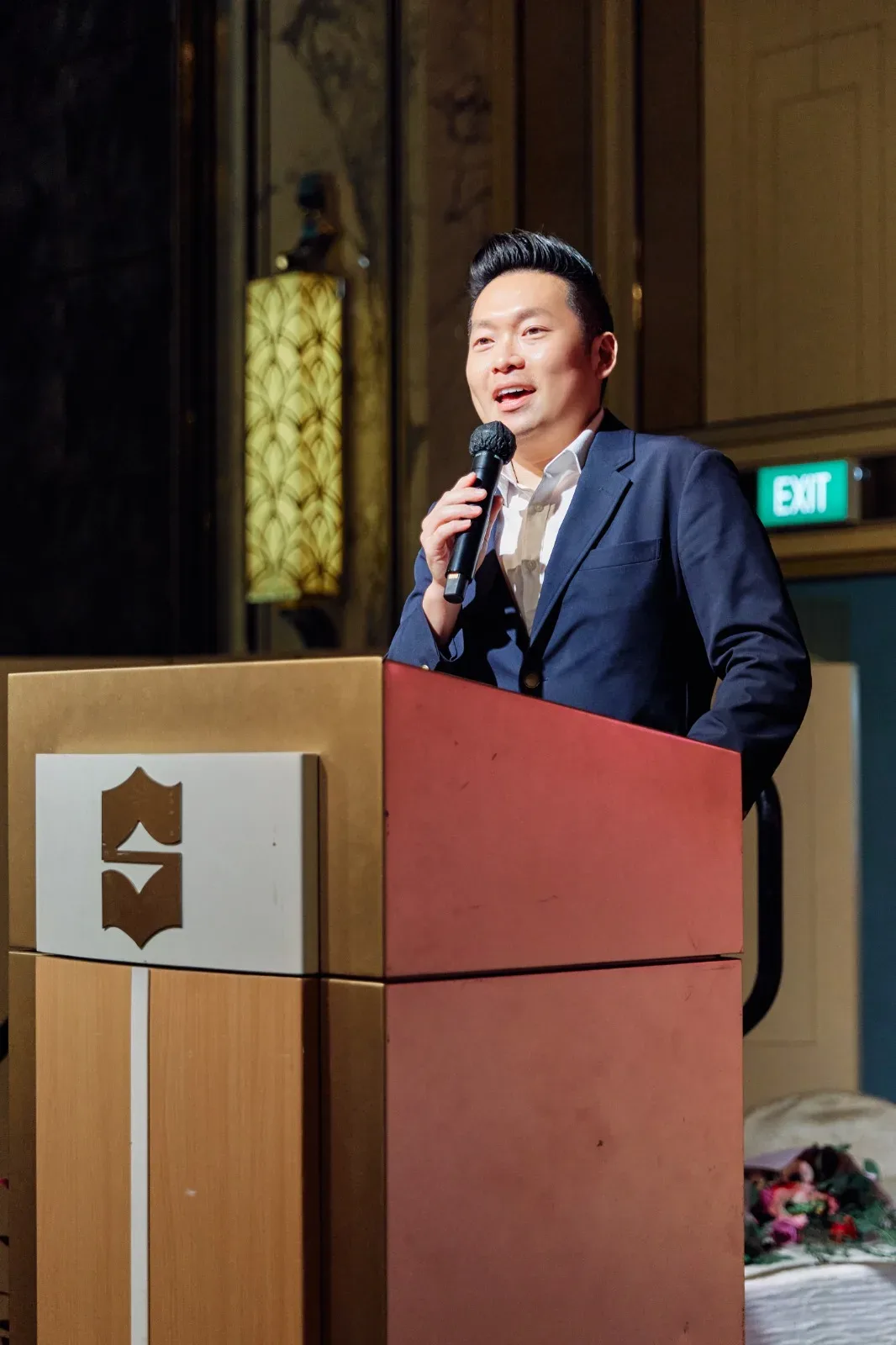 James Yang speaking at a lectern at a corporate event in Singapore