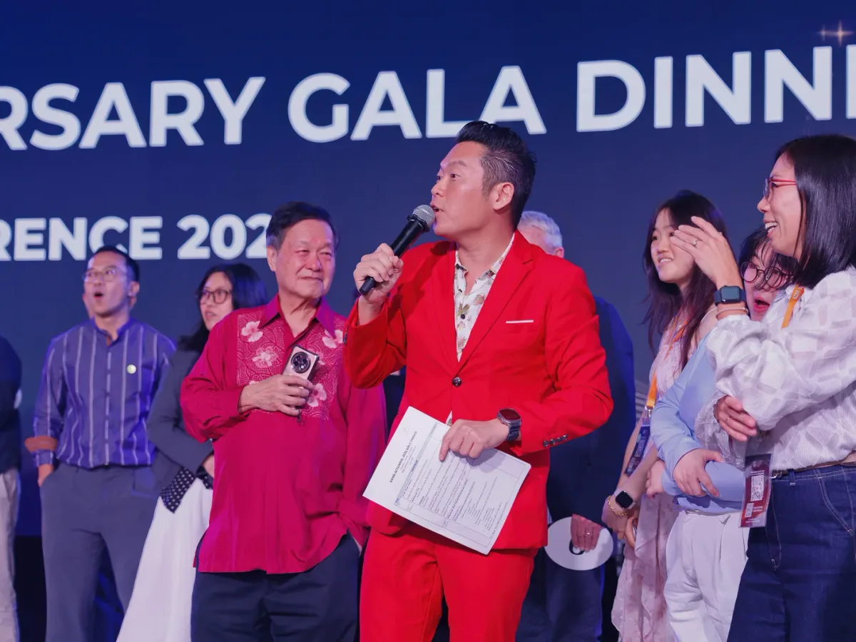 James Yang on stage in a red suit at the SAS 50th Anniversary Gala Dinner, Asian Actuarial Conference 2026