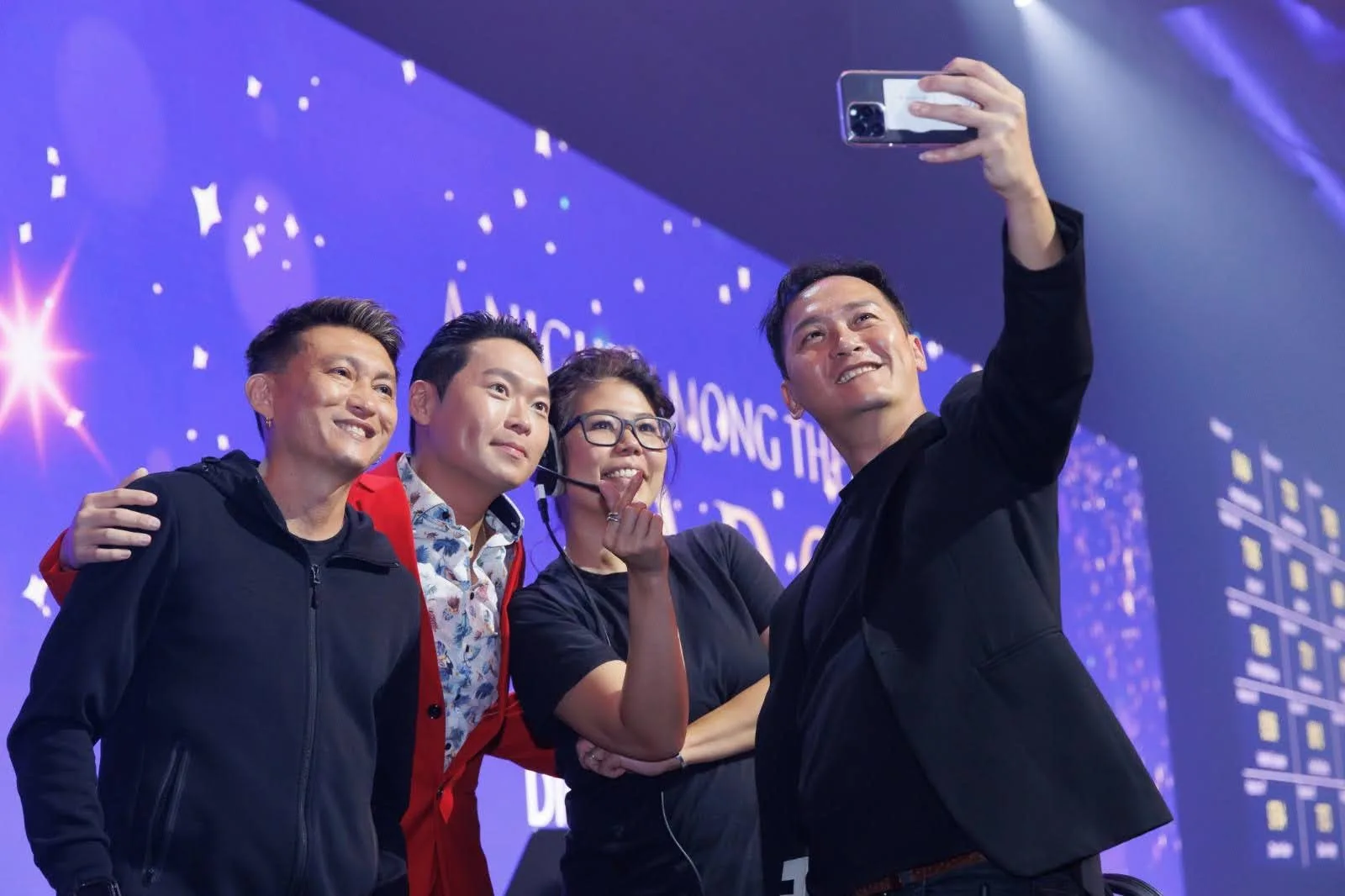 James Yang taking a selfie with guests on stage