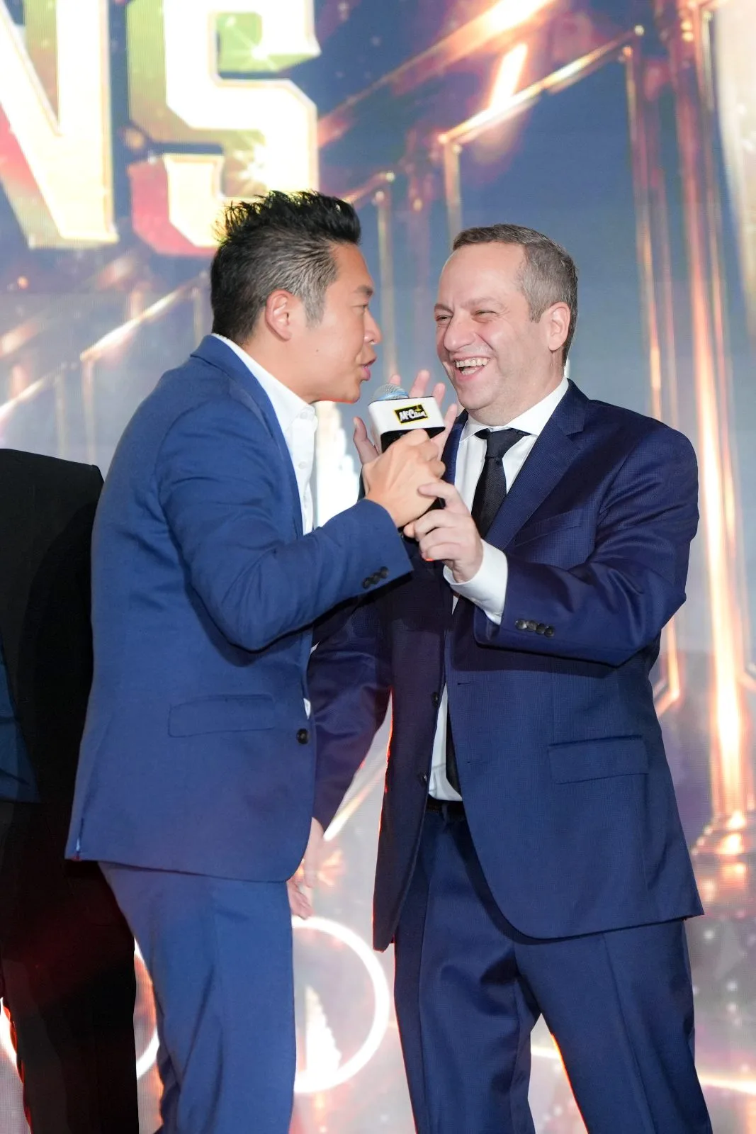 James Yang sharing the microphone with a guest at a dinner and dance