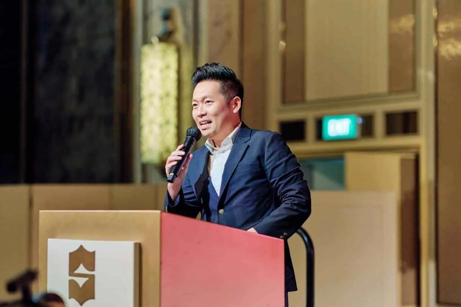 James Yang speaking at a lectern during a corporate event